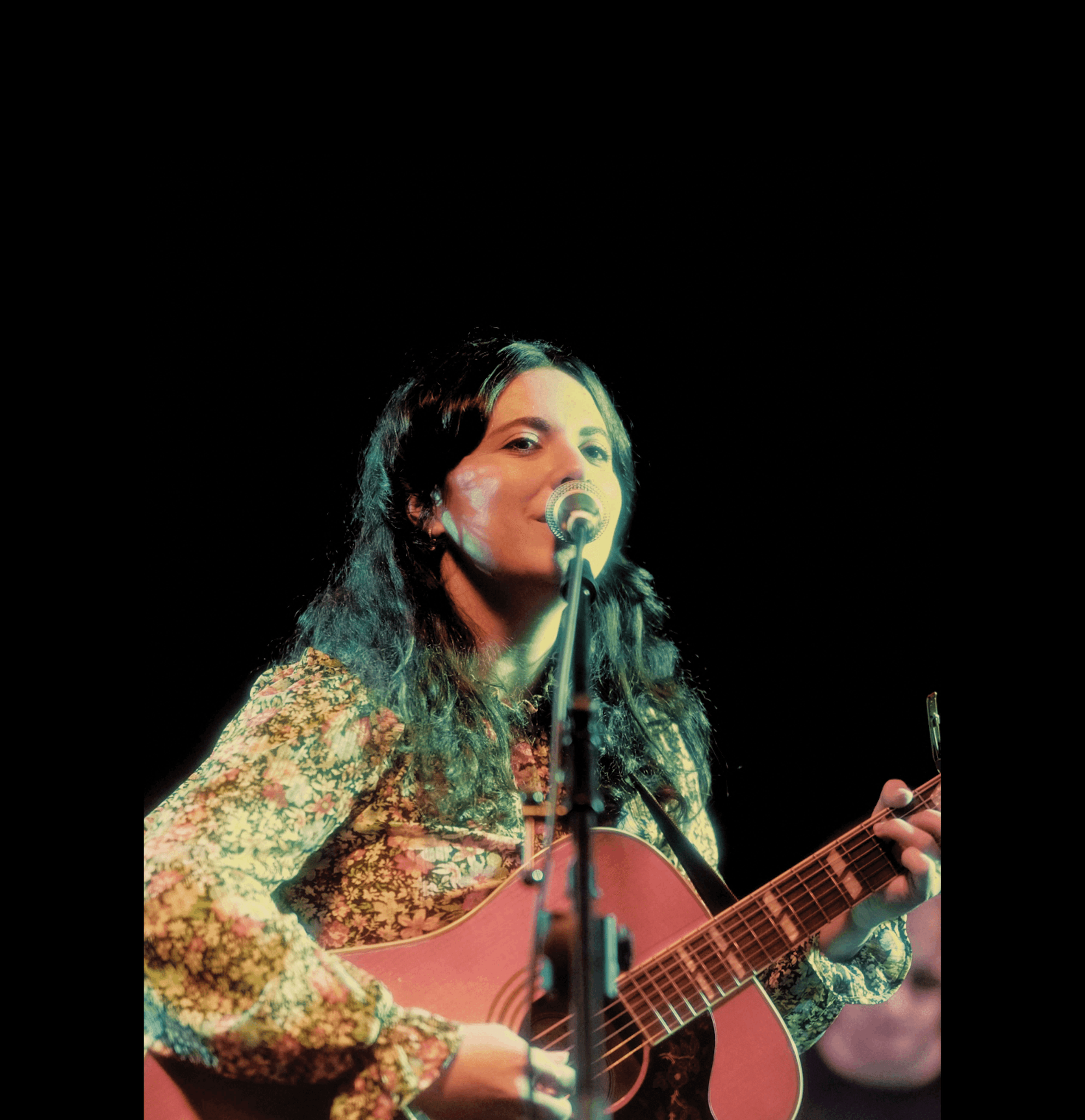 a woman playing an acoustic guitar in front of a microphone